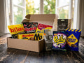 Swedish Licorice Taste Box Medium open on a dark wooden table by a bright window – Ahlgrens Bilar Saltlakrits, Malaco Gott & Blandat Salt, Malaco Djungelvrål, Marabou Black Saltlakrits, S-Märke Supersalt, Cloetta Polly Licorice, Dave & Jon's Dadlar Saltlakrits and Fazer Tyrkisk Peber inside
